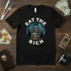 Eat The Rich t-shirt design with a skeleton holding cutlery in front of a treasure chest filled with riches