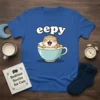 Eepy cat yawning in a teacup graphic on a blue t-shirt, designed for cat lovers