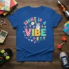 Blue t-shirt with colorful "EIGHT IS A VIBE" text, peace sign hand, flowers, and lightning bolts