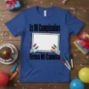 Blue t-shirt with "Es Mi Cumpleaños Firma Mi Camisa" text and a blank whiteboard for signatures, surrounded by party decorations
