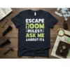 T-shirt with white and green text: ESCAPE ROOM RULES? ASK ME ABOUT IT!, featuring a keyhole graphic