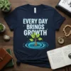 T-shirt with white text "EVERY DAY BRINGS GROWTH" and a green sapling growing in water