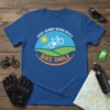 Blue t-shirt with "EVERY JOURNEY BEGINS WITH A BIKE SMILE" text and a bicycle graphic, sun, and rolling hills