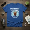 Everything Is Cool text with iced coffee graphic on a blue t-shirt, featuring waves and a crescent moon