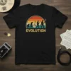 Black t-shirt with retro sunset graphic showing human evolution from ape to guitar player, text reads EVOLUTION