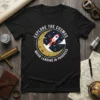 Black t-shirt with "Explore the Cosmos Moon Landing in Progress" text and a rocket ship launching from the moon graphic
