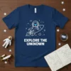 Navy t-shirt with "EXPLORE THE UNKNOWN" text and a white line-art astronaut riding a rocket in space