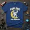 Astronaut graphic on a blue t-shirt with text "EXPLORE THE UNKNOWN" and a crescent moon design