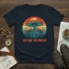 Retro sunset graphic tee with "Explore The Unseen" text and colorful mushrooms, navy blue shirt
