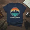 Navy t-shirt with "EXPLORE THE WILD" text and a vintage circle graphic featuring mountains, lake, and pine trees