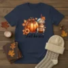 Fall basics graphic t-shirt with pumpkin, coffee cup, and football illustration, surrounded by autumn leaves