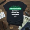 Navy blue t-shirt with "FATHERHOOD: OUTWIT OUTPLAY OUTLAST" in green and white text, featuring palm fronds and a survivor-style logo