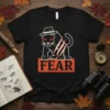 Black t-shirt with a white outline of a cat wearing a fedora and red glowing eyes, with the word FEAR