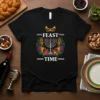 Black t-shirt with "Feast Time" text, a menorah, grapes, apples, and cornucopias, symbolizing Hanukkah and holiday feasting