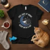 Black t-shirt with white text "Feel Safe At Night Sleep With A Cat" encircling a sleeping black cat on a