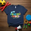 Navy blue t-shirt with colorful "Field Day Vibes" text and sunglasses graphic, representing school sports and outdoor fun