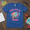 Blue t-shirt graphic with "First Day Of Grade" text and a colorful rocket ship launching through a galaxy, numbered 4