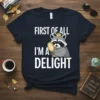 T-shirt with white text "FIRST OF ALL I'M A DELIGHT" and a cartoon raccoon wearing a crown and holding a