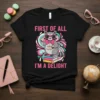 Raccoon sitting on books holding tea, text "First Of All I'm A Delight" in pink font on black t-shirt