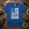 White "Fishing Freedom" text on a blue t-shirt, with an American flag design featuring fishing rods and fish
