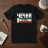 Black t-shirt with white text 'Чечня' above a flag design featuring mountains and gold emblem