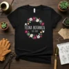 Flora Botanica Est. 2023 text inside a floral wreath on a black t-shirt design