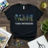 Black t-shirt with "Floral Watercolors" text and a row of blue and purple watercolor flowers above it