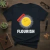 Flourish t-shirt with a smiling sun graphic and a red comb, featuring white text that says FLOURISH
