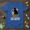 Black cat sitting on books with "Fluff Around And Find Out" text, holding a toy, on a blue t-shirt