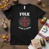 Black t-shirt with "FOLK FLORA & FAUNA" text and a circular folk art design featuring a tree, flowers, and animals