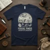 Fossil Finds Ancient Life Unearhred T-Shirt featuring a circular design with dinosaur skull, trilobite, fish skeleton, and ammonite fossils