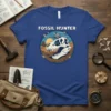 Fossil Hunter t-shirt design featuring a T-Rex skull, a person digging, and prehistoric insects in a desert landscape