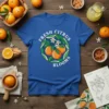 FRESH CITRUS BLOOMS text with a circular design of oranges and blossoms on a blue t-shirt