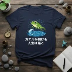 Japanese proverb "カエルが怖けも 人生は越こ" with a cute frog jumping in the rain and water ripples on a dark t-shirt