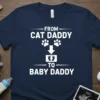 T-shirt with white text "FROM CAT DADDY TO BABY DADDY" and graphics of paw prints and baby feet