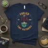 Navy t-shirt with "Fueled by Tea and Tiny Victories" text and a steaming teacup graphic, surrounded by stars and arrows