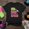 Black t-shirt with "Gag Me With A Spoon" text and a cartoon cassette tape holding a spoon. 80s retro design