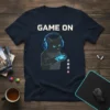 Game On text above a black cat wearing headphones and holding a video game controller, on a navy t-shirt
