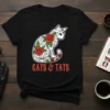 Black t-shirt with white cat decorated with red roses and green leaves, text reads GATS & TATS