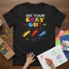 Get Your Cray On! text with three cartoon crayons in yellow, red, and blue on a black t-shirt
