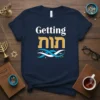 Navy blue t-shirt with "Getting חמסה" text and blue and white wavy graphic design, featuring Jewish holiday motifs