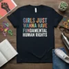 Girls Just Wanna Have Fundamental Human Rights text design in colorful block letters on a black t-shirt