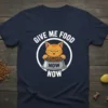 Give Me Food Now Now text with grumpy orange cat holding a food bowl on a navy blue t-shirt