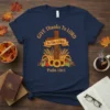 Navy t-shirt with "Give Thanks To Lord Psalm 136:1" text, a wooden cross, cornucopia, sunflowers, and wheat