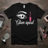 Glam squad text with an eye and mascara graphic on a black t-shirt, perfect for makeup lovers