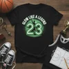Glow Like A Legend 23 basketball design with silhouette of player and radiant green background on a black t-shirt
