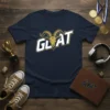 Navy blue t-shirt with the word "GOAT" in bold white and gold lettering, featuring a stylized goat head graphic