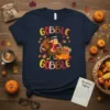Gobble Gobble Thanksgiving T-Shirt with a cartoon turkey wearing a hat and holding a basket of produce