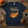 Grateful & Thankful text with cornucopia graphic filled with pumpkins, apples, and wheat on a navy t-shirt