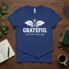 White text "GRATEFUL (each and every day)" with a leaf and arrow graphic on a blue t-shirt
